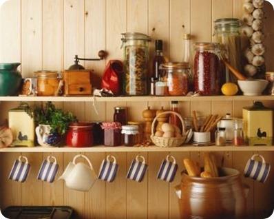 Dresser, shelves holding, jug, pickled produce, grinder, pasta in jar, lentils, salt and pepper pots, cups hanging from hooks, bread in jar, front view.