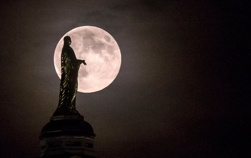 The full moon silhouettes the statue of the Virgin Mary on top the University of Notre Dame's golden dome on Monday, Sept. 8, 2014, in South Bend, Ind. (AP Photo/South Bend Tribune, Robert Franklin)